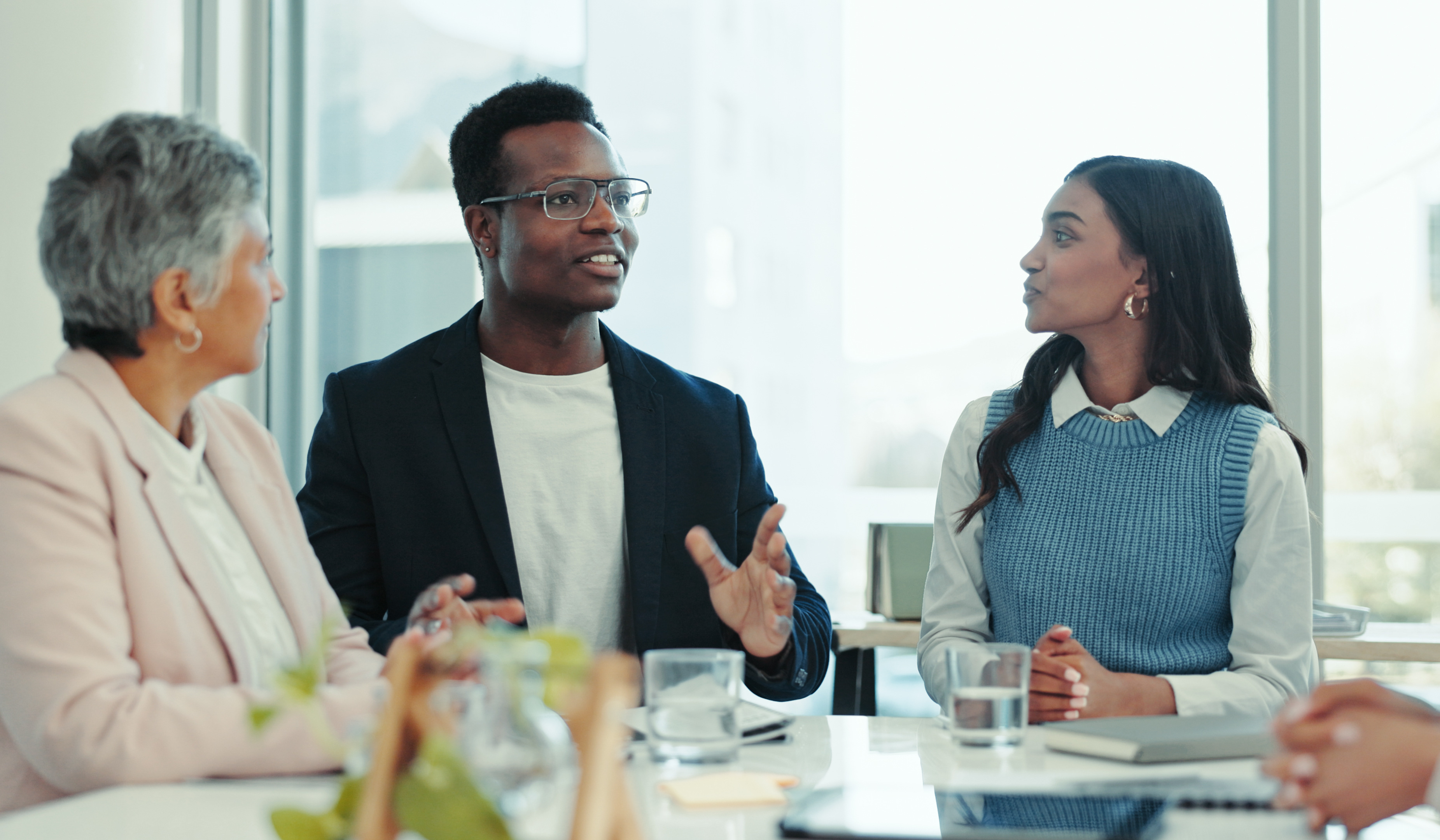 Three professionals sitting at a conference table discussing ideas