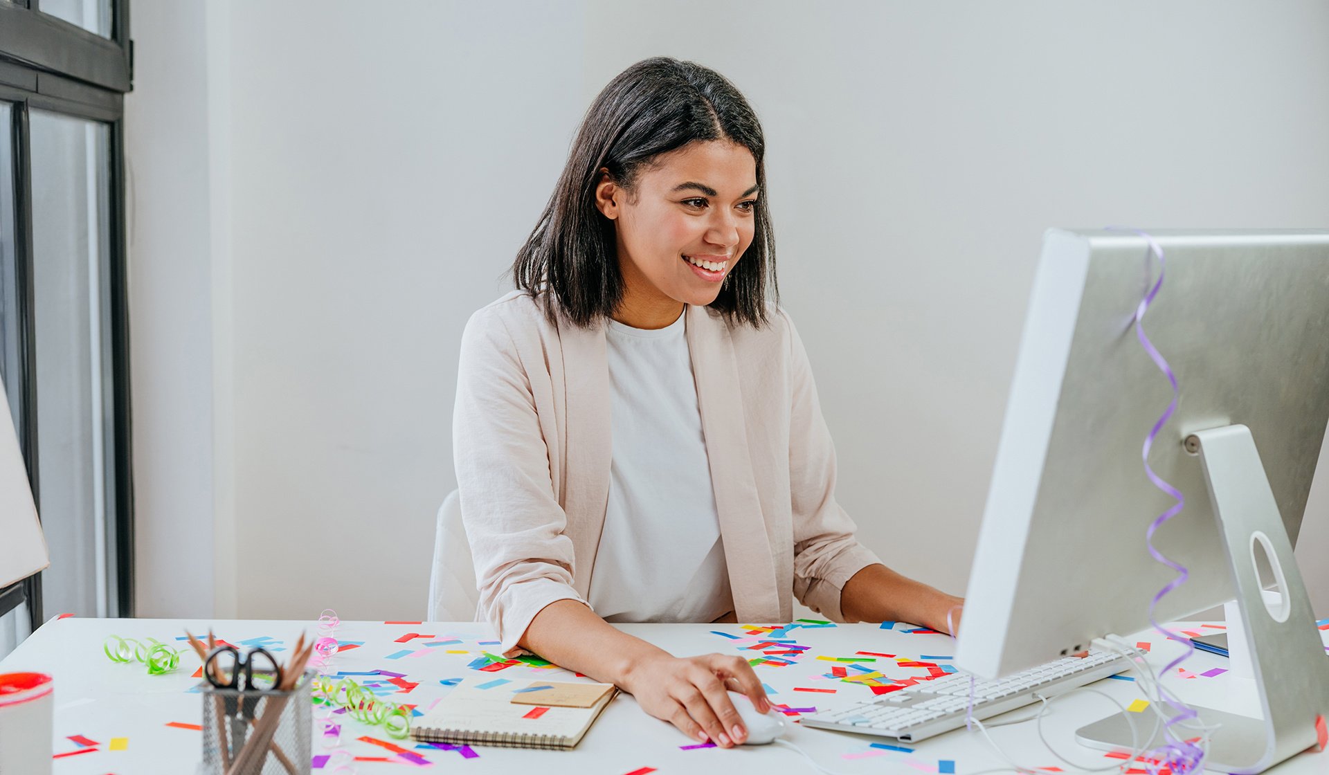 Woman at computer with confetti on the desk