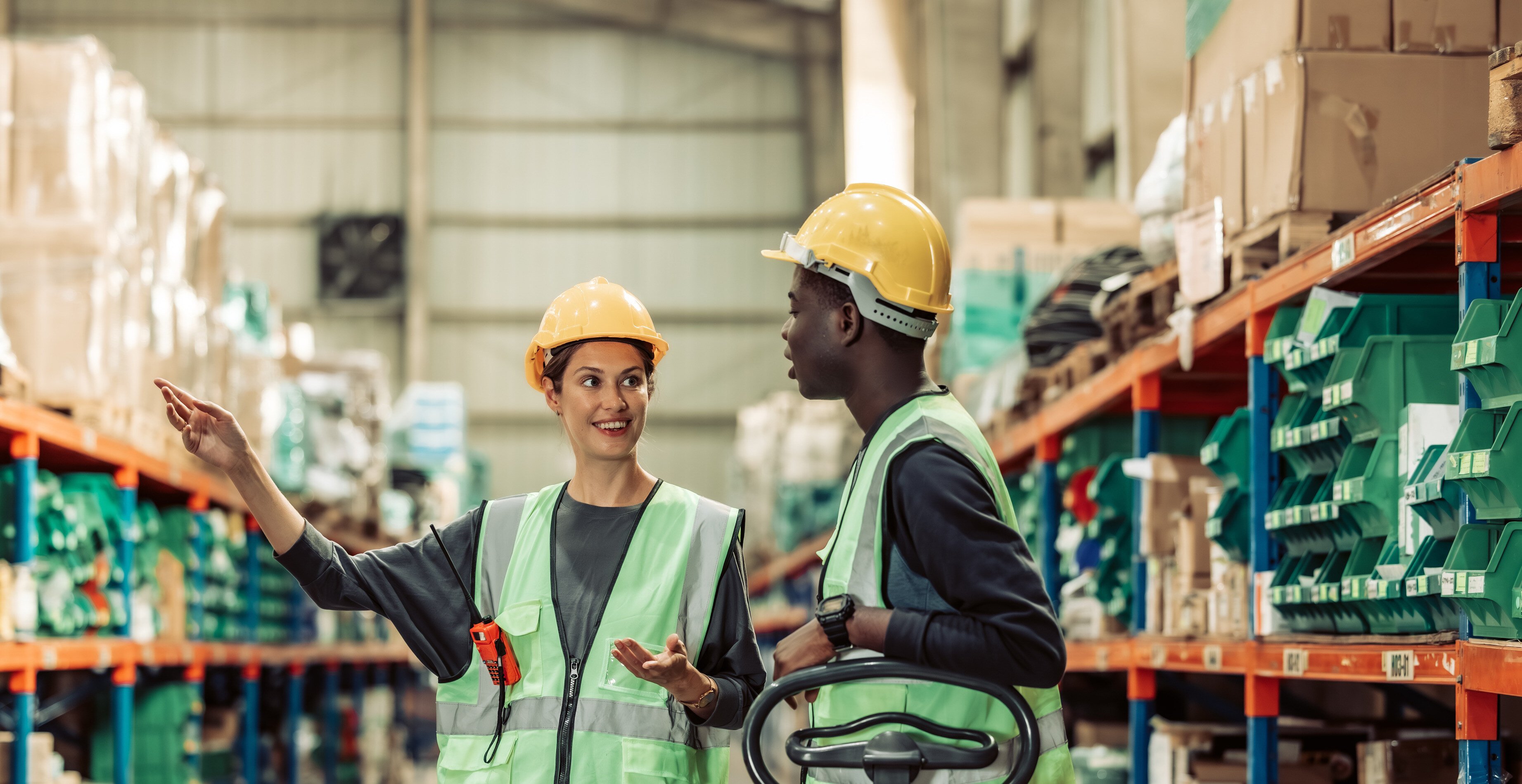 Two employees chat with one another in a warehouse.